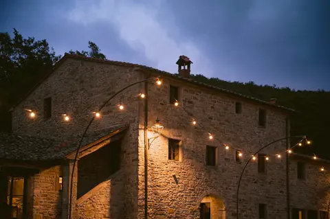 Warm lights across the stone walls of Villa Santarsa at dusk